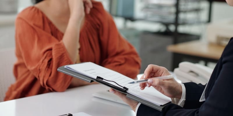 mulher sentada à mesa sendo atendida por um advogado especialista que explica sobre Auxílio Doença.